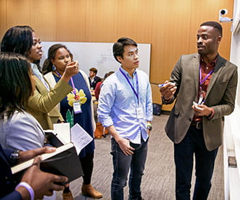 A group of students circle around a whiteboard for a discussion in a classroom